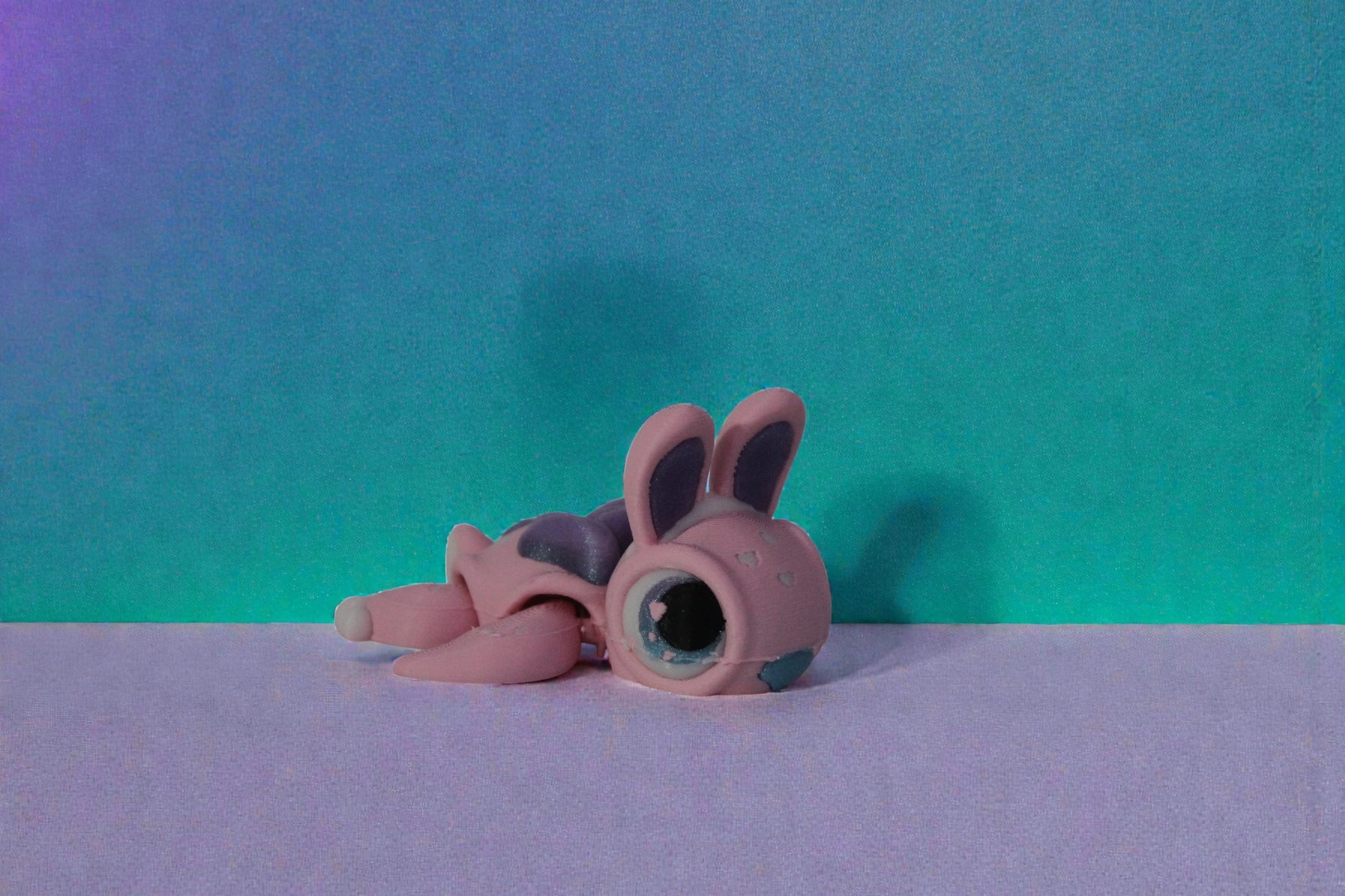 Side angle view of a pastel pink articulated bunny turtle with shimmer purple shell and large glossy eyes on a neutral background.
