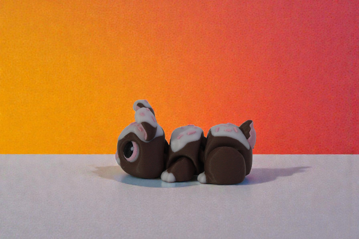 Side profile of articulated chocolate bunny decor showing rounded body segments and tail detail, dessert inspired 3D printed shelf collectible.
