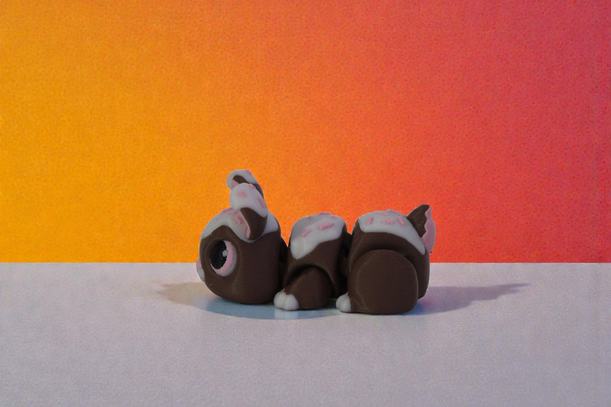 Side profile of articulated chocolate bunny decor showing rounded body segments and tail detail, dessert inspired 3D printed shelf collectible.
