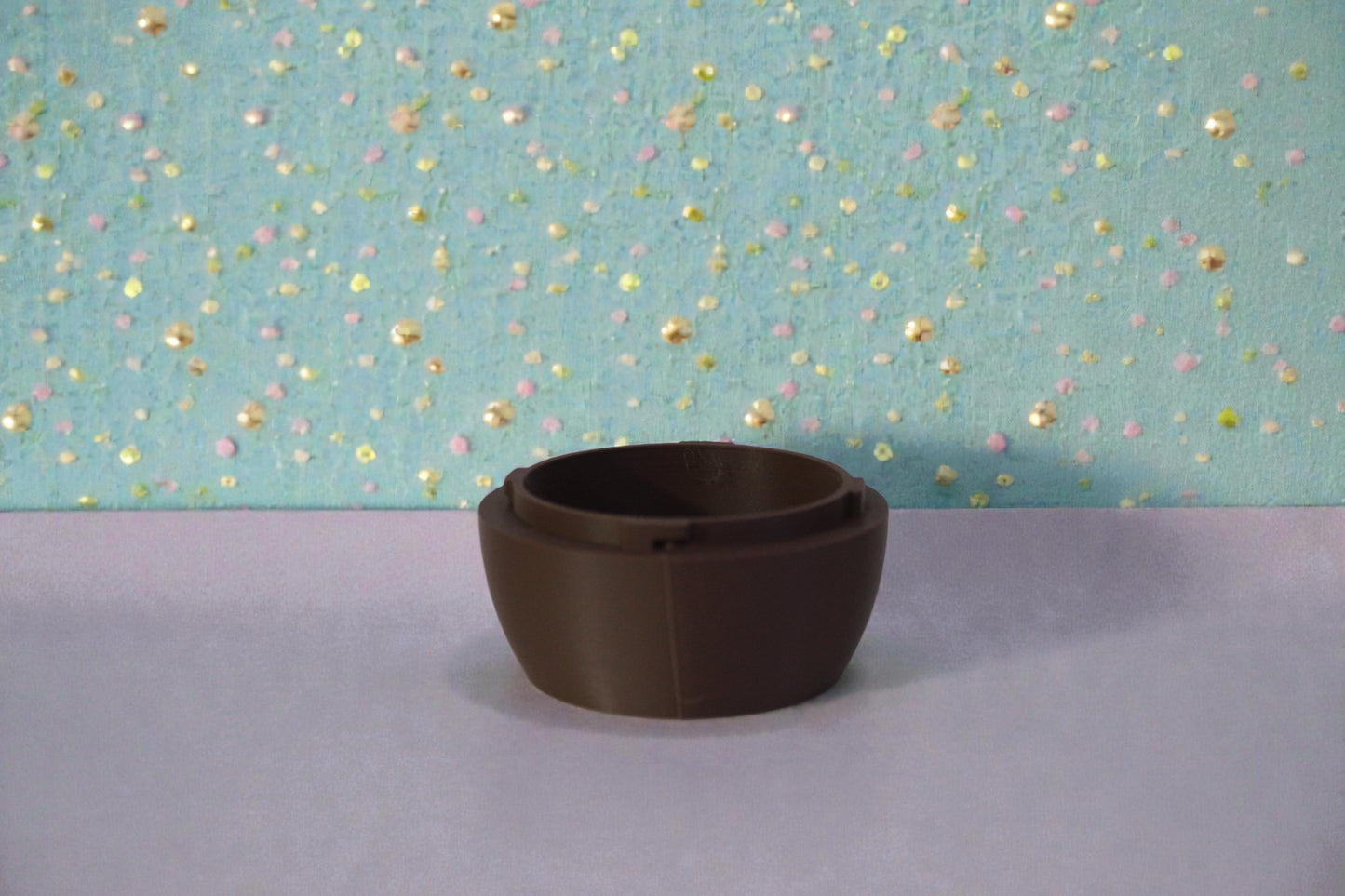 Bottom half of chocolate brown 3D printed egg container showing twist lock rim and smooth rounded shape, decorative display piece.